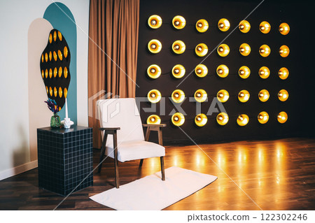 armchair with light fabric against of incandescent lamps. area with armchair and bright floor lamps 122302246