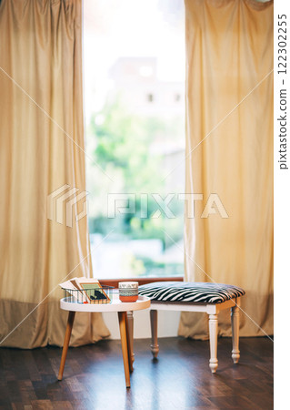 chair with striped fabric and white table against window background. photo zone with coffee table chair with striped fabric and white table against window background. photo zone with coffee table 122302255