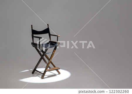 Directors chair stands in the beam of light. Space for text. Vacant chair. The concept of selection and casting. Shadow and light. 122302260