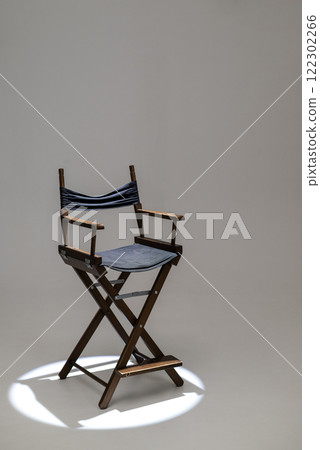 Directors chair stands in the beam of light. Space for text. Vacant chair. The concept of selection and casting. Shadow and light. Directors chair stands in the beam of light. Space for text. Vacant chair. The concept of selection and casting. Shadow and light. 122302266