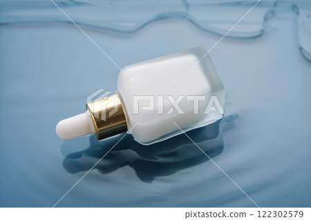 Bottle with white moisturizing serum in water on blue background. 122302579
