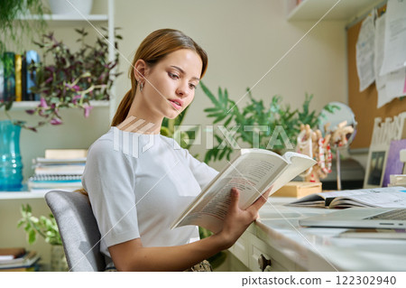 Young teenage female reading book, novel, fiction educational literature at home Young teenage female reading book, novel, fiction educational literature at home 122302940