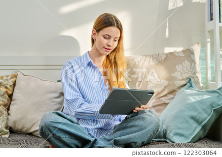 Portrait of female student on couch with digital tablet, studying at home Portrait of female student on couch with digital tablet, studying at home 122303064