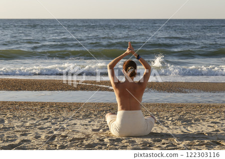 Woman meditating on beach 122303116