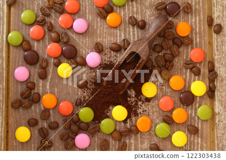 multi-colored candy and roasted coffee beans on brown background. With wooden spoon. 122303438