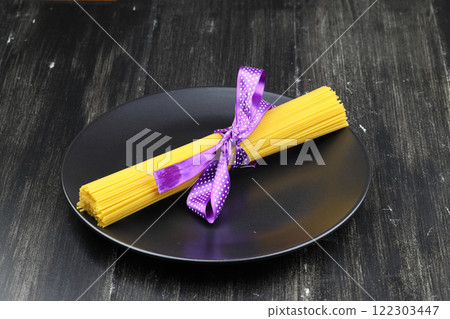Flat lay of spaghetti for cooking italian pasta over black background. Top view of traditional italian cusine concept Flat lay of spaghetti for cooking italian pasta over black background. Top view of traditional italian cusine concept 122303447