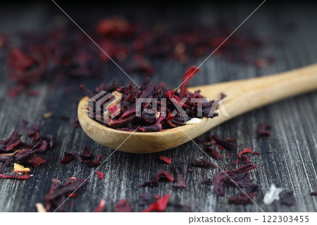 Karkade tea. Hibiscus tea leaves in wooden spoon isolated on wooden background. File contains clipping path. Top view. Selective focus. 122303455