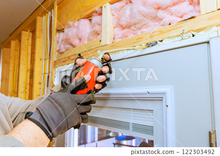 Person applies weatherproofing foam spray around door frame during home renovation residential setting. Person applies weatherproofing foam spray around door frame during home renovation residential setting. 122303492