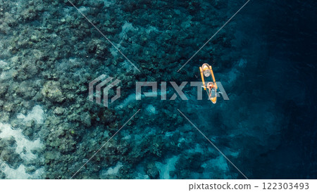 Woman kayaking in clear blue ocean on transparent kayak. Above drone view with copy space 122303493