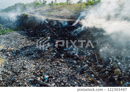 Burning landfill emitting smoke, highlighting environmental pollution and waste management challenges in Bali, Indonesia 122303497