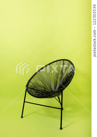 black metal chair made of artificial rattan light green background. furniture on a paper background black metal chair made of artificial rattan light green background. furniture on a paper background 122303539
