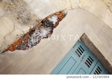 Breach in the plastered wall of a stone house 122303904