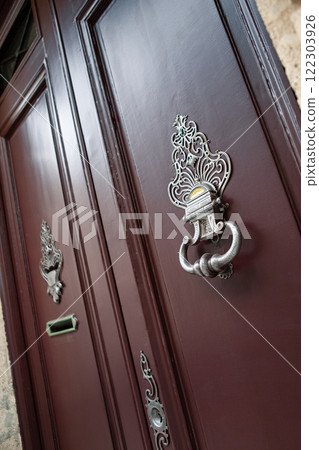 Elegant door knocker on a facade Elegant door knocker on a facade 122303926
