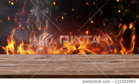 empty barbecue BBQ grill with flaming fire and ember charcoal on black background and wood board table 122303963