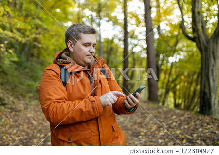Young Caucasian 30s man backpacker with smartphone catching signal at wooden forest. Road trip, transport, travel, technology and people concept. High quality photo Young Caucasian 30s man backpacker with smartphone catching signal at wooden forest. Road trip, transport, travel, technology and people concept. High quality photo 122304927