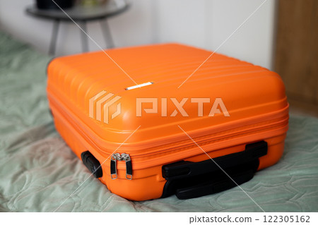 Big orange suitcase on the bed in light room. Baggage case packing getting ready to travel trip vacation. Lifestyle, adventure and tourism concept. 122305162