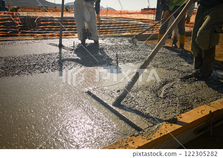 Construction workers level freshly cast concrete with bull float Construction workers level freshly cast concrete with bull float 122305282