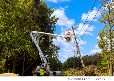 Power line worker repairs installs equipment on utility pole using hydraulic lift. Power line worker repairs installs equipment on utility pole using hydraulic lift. 122307080