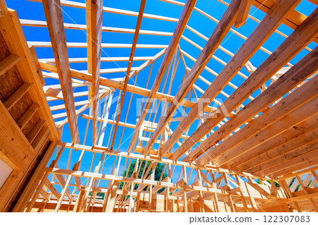 An open roof structure of wooden beams with progressing structural framework for skeletal frames on large construction site 122307083