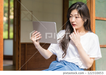 驚訝的年輕女子看著平板電腦 122310853