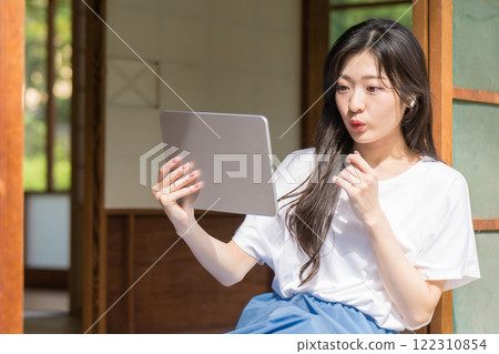 驚訝的年輕女子看著平板電腦 122310854