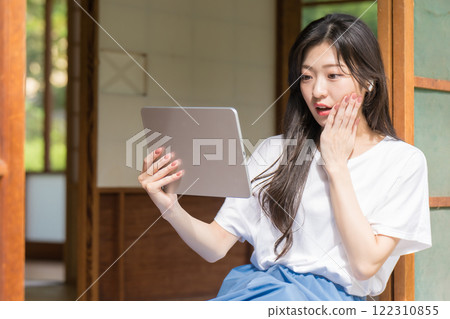 驚訝的年輕女子看著平板電腦 驚訝的年輕女子看著平板電腦 122310855