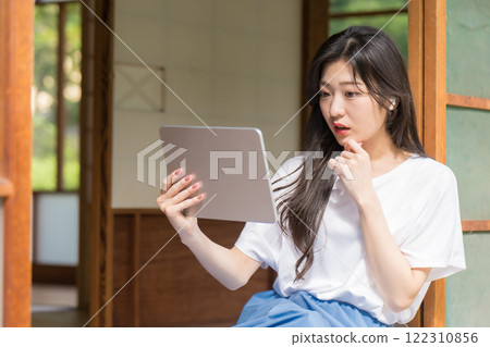 驚訝的年輕女子看著平板電腦 驚訝的年輕女子看著平板電腦 122310856
