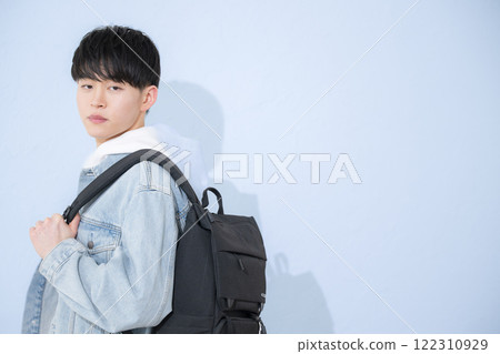 Image of a college student or young man in his 20s carrying a backpack, looking at the camera 122310929