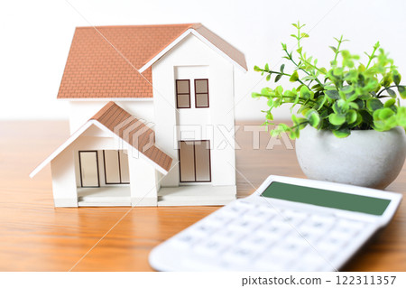 Real estate image of a house model and a calculator 122311357