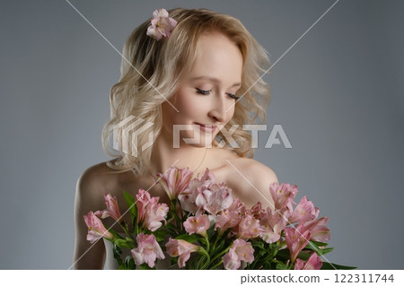 Model with bouquet of pink flowers in soft light setting indoors 122311744