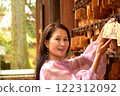 Smiling senior woman hanging a votive plaque 122312092