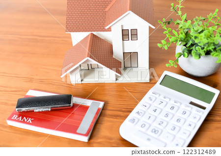 A desk with a model of a house, a calculator and a bankbook 122312489