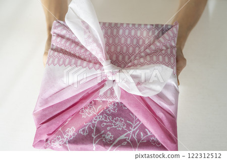 Hands holding a New Year's food box wrapped in a furoshiki Hands holding a New Year's food box wrapped in a furoshiki 122312512