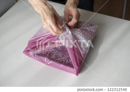 Hands unravelling furoshiki 122312540