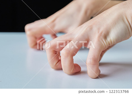 The hands of a person expressing irritation by digging their fingernails into the ground 122313766
