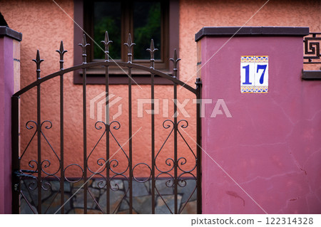 Ornate iron gate and pink wall with number 17 in spanish style architecture Ornate iron gate and pink wall with number 17 in spanish style architecture 122314328