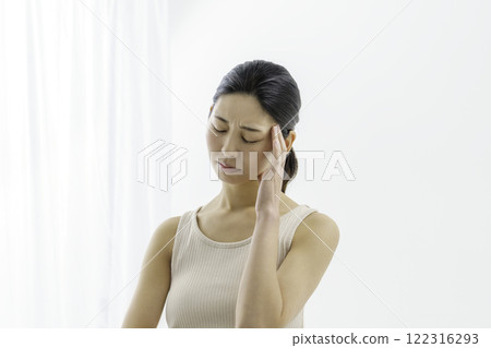 Young woman with a troubled face holding her forehead on a white background, headache, illness Young woman with a troubled face holding her forehead on a white background, headache, illness 122316293
