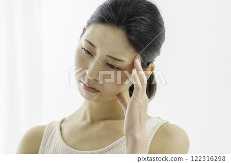 Young woman with a troubled face holding her head on a white background, headache, illness Young woman with a troubled face holding her head on a white background, headache, illness 122316298