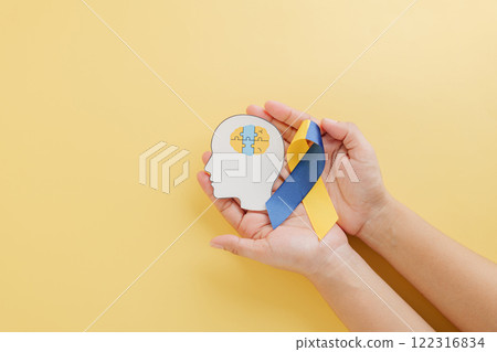 Hands hold a head with puzzle pieces and a ribbon for Down Syndrome. Advocating global awareness 122316834