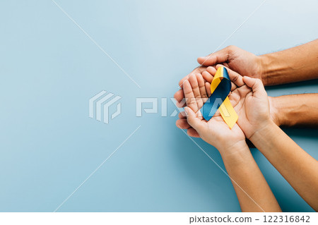 Down Syndrome awareness, hands hold a ribbon on blue background. Highlighting Down Syndrome Day Down Syndrome awareness, hands hold a ribbon on blue background. Highlighting Down Syndrome Day 122316842