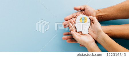 Hands holding a brain jigsaw in a head paper cut symbolize Down Syndrome awareness. 122316843