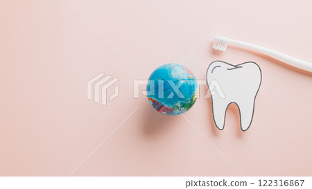 World Dentist Day concept: paper tooth, toothbrush, and world on pink. 122316867