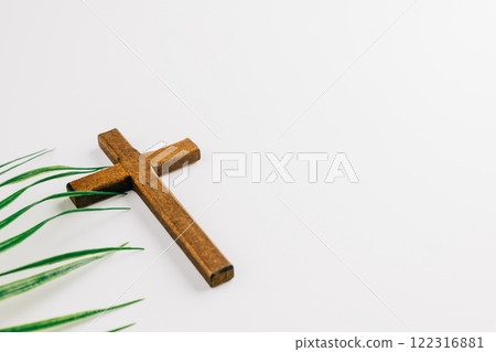 Wooden cross and green palm fronds on white background. Simple, minimalist design. Perfect for religious celebrations. 122316881