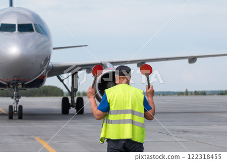 Aircraft marshalling at the aiport apron. Passenger airplane meeting 122318455