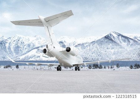 White luxury executive airplane at the airport apron on the background of high picturesque snow capped mountains White luxury executive airplane at the airport apron on the background of high picturesque snow capped mountains 122318515