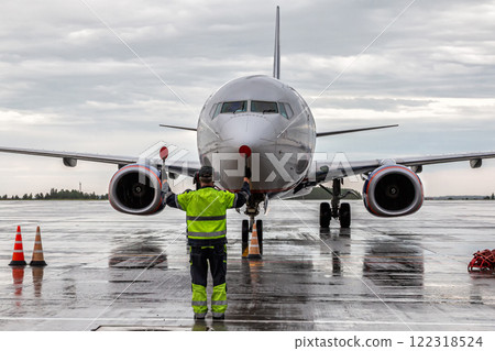 Airplane marshalling at the aiport apron in rainy weather. Passenger aircraft meeting 122318524
