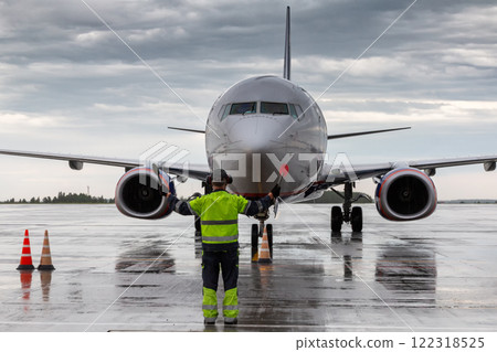 Aircraft marshalling at the aiport in rainy weather. Passenger airplane meeting Aircraft marshalling at the aiport in rainy weather. Passenger airplane meeting 122318525
