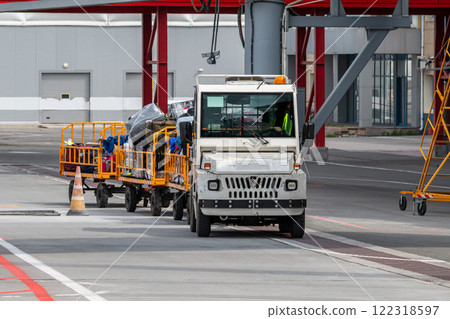 Tow tractor pulling luggage carts at airport apron Tow tractor pulling luggage carts at airport apron 122318597