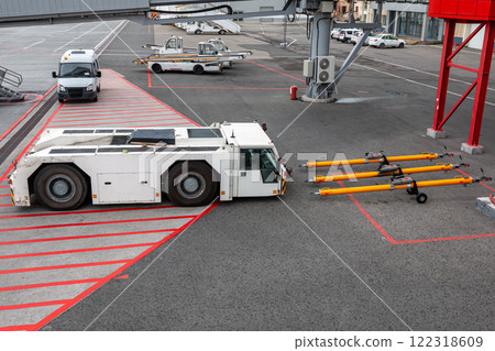 Aircraft tow tractor near towbars, self-propelled conveyor belt loaders and minibus at the airport apron Aircraft tow tractor near towbars, self-propelled conveyor belt loaders and minibus at the airport apron 122318609