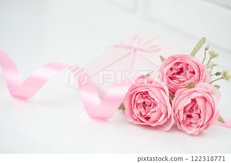Three pink roses with ribbon and giftbox on the white table 122318771